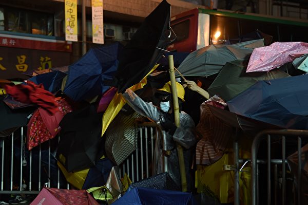Demonstrators protect themselves with umbrellas during a stand-off with police during ongoing protests in Hong Kong on November 6, 2016. Hong Kong police used pepper spray November 6 to drive back hundreds of protesters angry at China's decision to intervene in a row over whether two pro-independence lawmakers should be barred from the city's legislature. In chaotic scenes reminiscent of mass pro-democracy protests in 2014, demonstrators charged metal fences set up by police outside China's liaison office in the semi-autonomous city. / AFP / Anthony WALLACE (Photo credit should read ANTHONY WALLACE/AFP/Getty Images)
