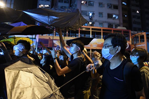 Demonstrators carry umbrellas during a stand-off with police during ongoing protests in Hong Kong on November 6, 2016. Hong Kong police used pepper spray November 6 to drive back hundreds of protesters angry at China's decision to intervene in a row over whether two pro-independence lawmakers should be barred from the city's legislature. In chaotic scenes reminiscent of mass pro-democracy protests in 2014, demonstrators charged metal fences set up by police outside China's liaison office in the semi-autonomous city. / AFP / Anthony WALLACE (Photo credit should read ANTHONY WALLACE/AFP/Getty Images)