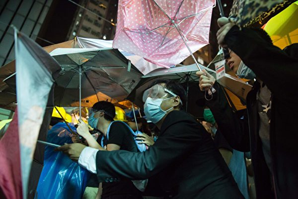 A protester wearing a mask hides behind umbrellas amid ongoing protests and clashed with police in Hong Kong on November 6, 2016. Hong Kong police used pepper spray November 6 to drive back hundreds of protesters angry at China's decision to intervene in a row over whether two pro-independence lawmakers should be barred from the city's legislature. In chaotic scenes reminiscent of mass pro-democracy protests in 2014, demonstrators charged metal fences set up by police outside China's liaison office in the semi-autonomous city. / AFP / ISAAC LAWRENCE (Photo credit should read ISAAC LAWRENCE/AFP/Getty Images)