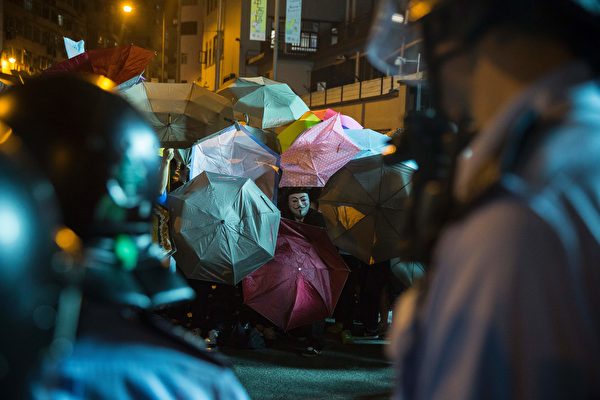 A protester wearing a mask hides behind umbrellas amid ongoing protests and clashed with police in Hong Kong on November 6, 2016. Hong Kong police used pepper spray November 6 to drive back hundreds of protesters angry at China's decision to intervene in a row over whether two pro-independence lawmakers should be barred from the city's legislature. In chaotic scenes reminiscent of mass pro-democracy protests in 2014, demonstrators charged metal fences set up by police outside China's liaison office in the semi-autonomous city. / AFP / ISAAC LAWRENCE (Photo credit should read ISAAC LAWRENCE/AFP/Getty Images)