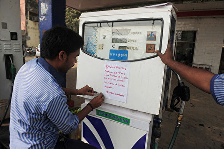印度加油站工作人員貼通告告知，在新貨幣流通之際，要求消費者需提供正確的盧比金額。(SANJAY KANOJIA/AFP/Getty Images)