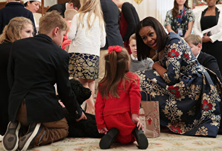 WASHINGTON, DC - NOVEMBER 29: U.S. first lady Michelle Obama talks to a little girl as first dog Sunny looks on in the State Dining Room as she hosts military families to the White House to view the 2016 holiday decorations November 29, 2016 in Washington, DC. "The Gift of the Holidays" is the theme of this year's White House holiday decorations. (Photo by Alex Wong/Getty Images)