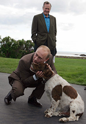 俄罗斯总统普京拜访前总统布什时拥抱他的爱犬。(MIKHAIL KLIMENTYEV/AFP/Getty Images)
