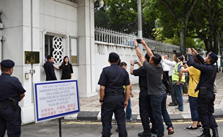 法輪功學員代表到中共駐馬大使館遞交抗議信，引起多位警官的關注。 （吳俐穎／大紀元）