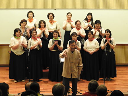 旅奧音樂家謝英杰老師（前立者），在「平安喜樂合唱音樂會」中，宣佈將指揮棒傳承給團長蕭麗華。（蔡上海／大紀元）