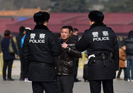 Chinese police question a man (C) in Tiananmen Square, next to the Great Hall of the People, the venue for upcoming meetings of China's legislature in Beijing on March 2, 2015. China's Communist Party-controlled legislature, the National People's Congress (NPC), gathers in the capital this week with the "rule of law" high on the agenda. AFP PHOTO / Greg BAKER (Photo credit should read GREG BAKER/AFP/Getty Images)
