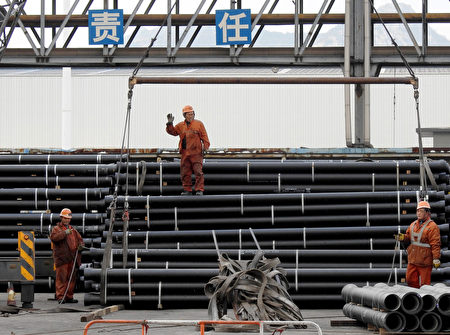中國鋼鐵業勞工正在準備將鋼管裝載到卡車上。(STR/AFP/Getty Images)