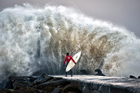 COLERAINE, NORTHERN IRELAND - DECEMBER 22: A huge wave crashes against Castlerock pier as 圣诞新年期间两股台风席卷英国。图为一名职业冲浪选手在北爱的Coleraine等待巨浪过去。(Photo by Charles McQuillan/Getty Images)